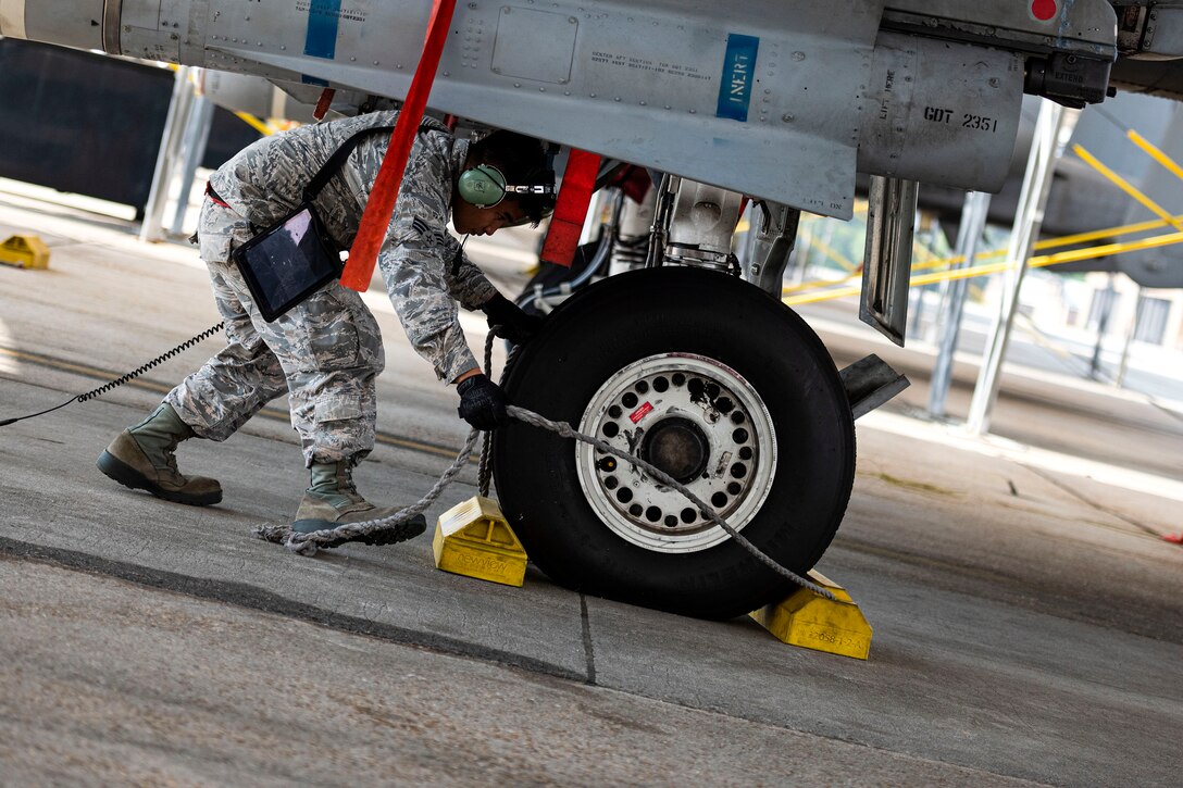 Photo of Airman removing chocks.