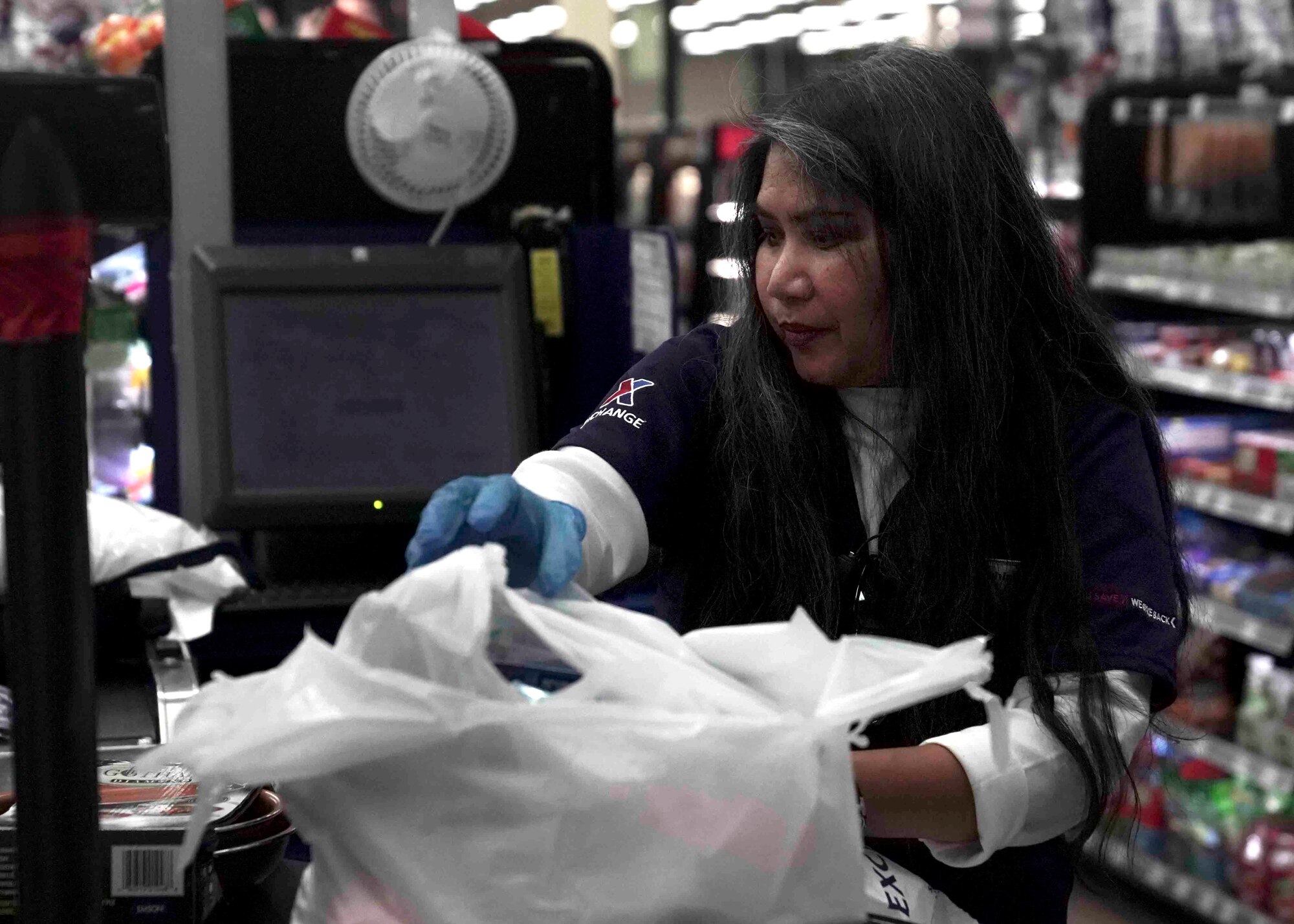 Josephine Rice, a cashier, packs a customer’s items at the Exchange on Nellis Air Force Base, Nevada, March 24, 2020. The Exchange staff cleans and sanitizes work areas more frequently to protect customers and employees during the COVID-19 pandemic. (U.S. Air Force photo by Senior Airman Stephanie Gelardo)