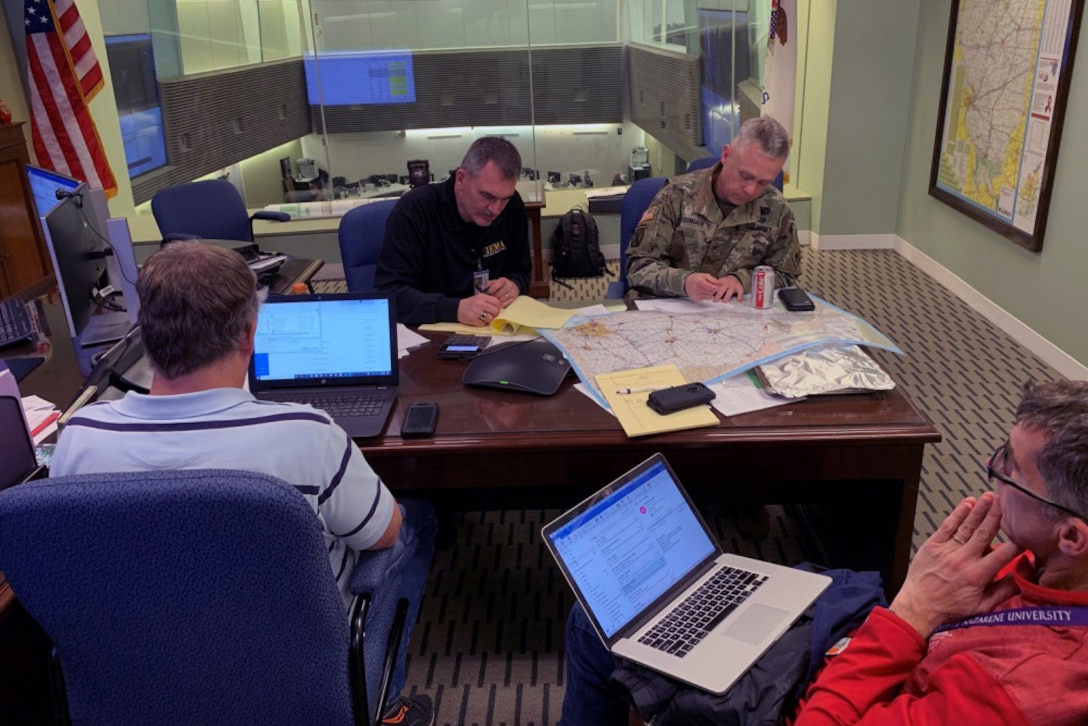 Two men seated at a table go over plans.