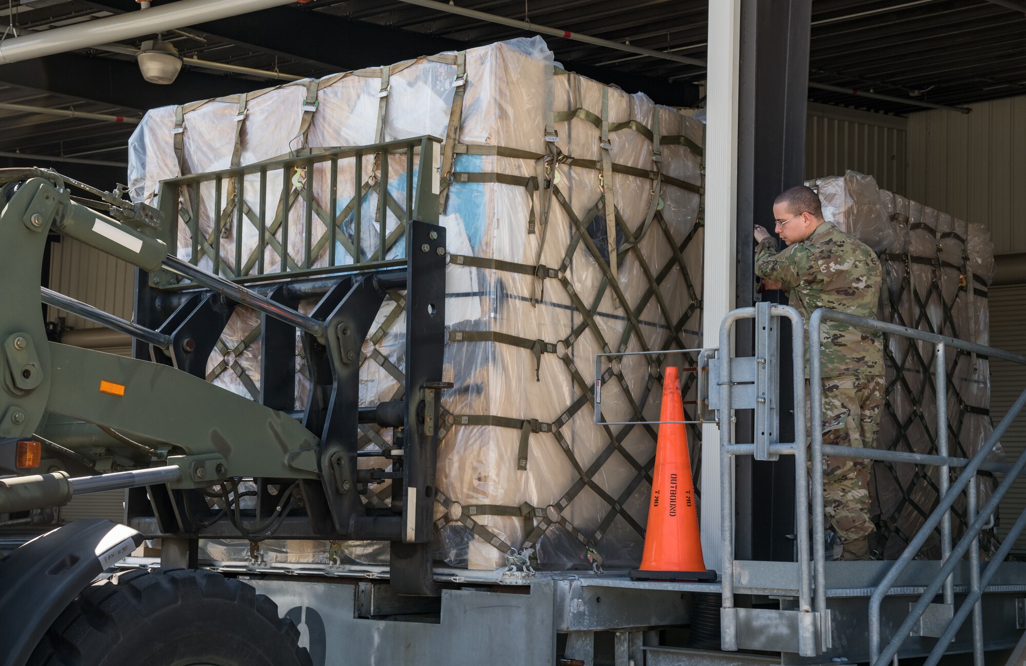 Airman 1st Class Emmanuel Arroyo, 436th Aerial Port Squadron traffic management office, marshals a 10K all-terrain forklift driven by Eric Banks, 436th APS, as they load a pallet onto a trailer March 26, 2020, at Dover Air Force Base, Delaware. Arroyo and Banks loaded numerous pallets onto the trailer as required airlift operations continued during the evolving COVID-19 pandemic. (U.S. Air Force photo by Roland Balik)