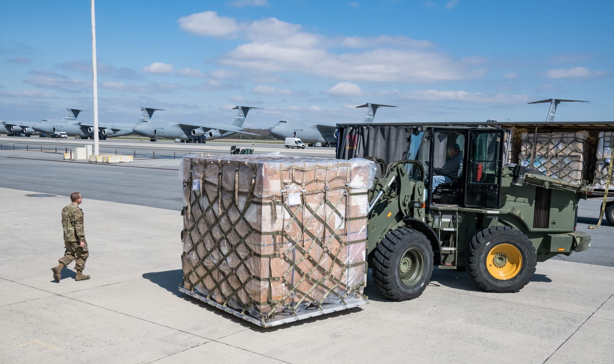 Airman 1st Class Emmanuel Arroyo, 436th Aerial Port Squadron traffic management office, marshals a 10K all-terrain forklift driven by Eric Banks, 436th APS, March 26, 2020, at Dover Air Force Base, Delaware. Arroyo and Banks loaded numerous pallets onto the trailer as required airlift operations continued during the evolving COVID-19 pandemic. (U.S. Air Force photo by Roland Balik)