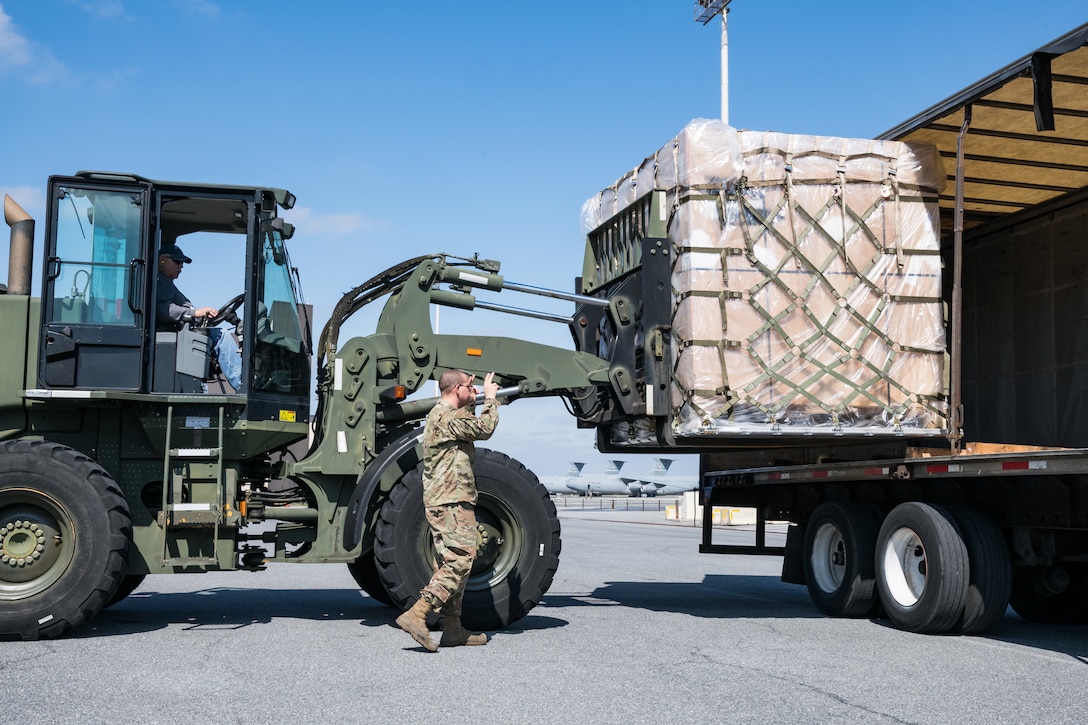 Airman 1st Class Emmanuel Arroyo, 436th Aerial Port Squadron traffic management office, marshals a 10K all-terrain forklift driven by Eric Banks, 436th APS, as they load a pallet onto a trailer March 26, 2020, at Dover Air Force Base, Delaware. Arroyo and Banks loaded numerous pallets onto the trailer as required airlift operations continued during the evolving COVID-19 pandemic. (U.S. Air Force photo by Roland Balik)