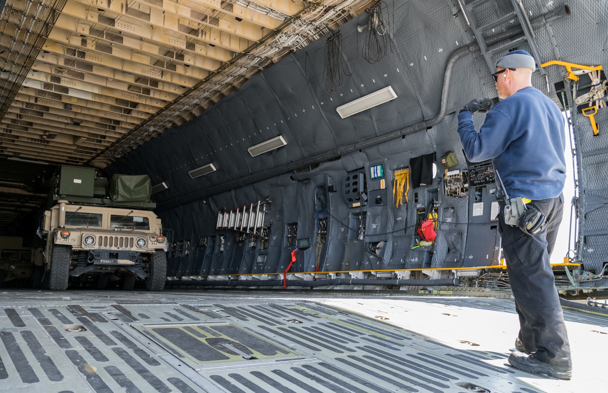 Dane Coward, 436th Aerial Port Squadron ramp supervisor, marshals a humvee in the cargo compartment of a C-5M Super Galaxy, March 26, 2020, at Dover Air Force Base, Delaware. Coward and his crew unloaded numerous humvees off the Super Galaxy as required airlift operations continued during the evolving COVID-19 pandemic. (U.S. Air Force photo by Roland Balik)