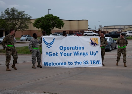 Airmen in Training leaders hold up a banner at Sheppard Air Force Base, Texas, March 27, 2020. The Airmen in Training are welcoming their new wingmen who are arriving via air lift to Sheppard. Usually the newest Airmen will arrive by bus, but to mitigate exposure Air Education and Training command opted to transport them via air lift. (U.S. Air Force photo by Senior Airman Pedro Tenorio)