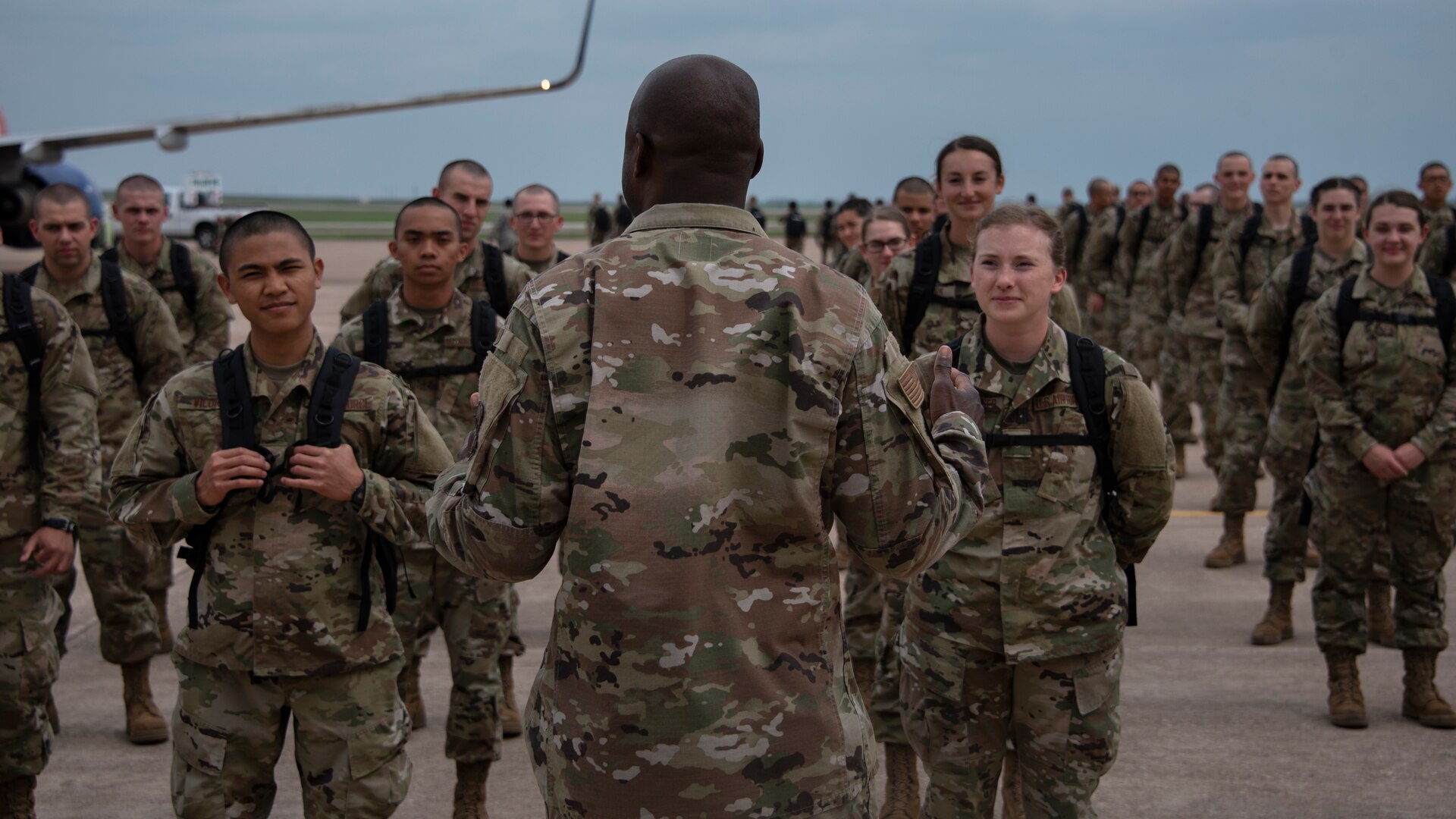 Col. Kenyon Bell, 82nd Training Wing commander, briefs the newest basic military training graduates once they off load from a plane at Sheppard Air Force Base, Texas, March 27, 2020. Bell greeted the newest Airmen by explaining why technical training continues as they are deemed mission essential and thanked the newest Airmen for their commitment to the Air Force. (U.S. Air Force photo by Senior Airman Pedro Tenorio)