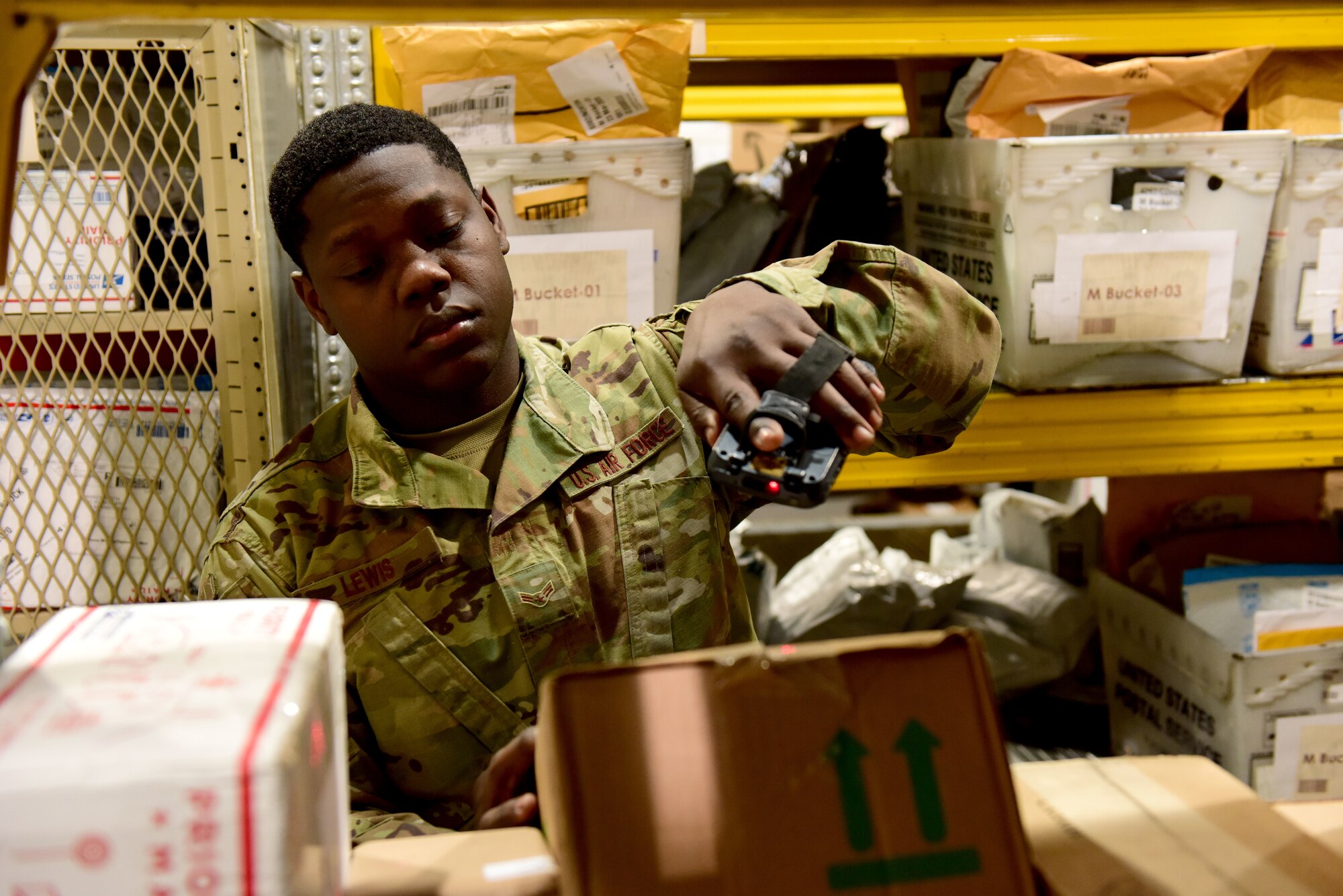 U.S. Air Force Airman 1st Class DeAnthony Lewis, 31st Force Support Squadron postal clerk, scans the label of a package at the Aviano Post Office, Aviano Air Base, Italy, March 25, 2020. Boxes entering the post office are scanned several times, entering them into the system and sending an email to the recipient notifying them of the package’s arrival. (U.S. Air Force photo by Staff Sgt. Kelsey Tucker)
