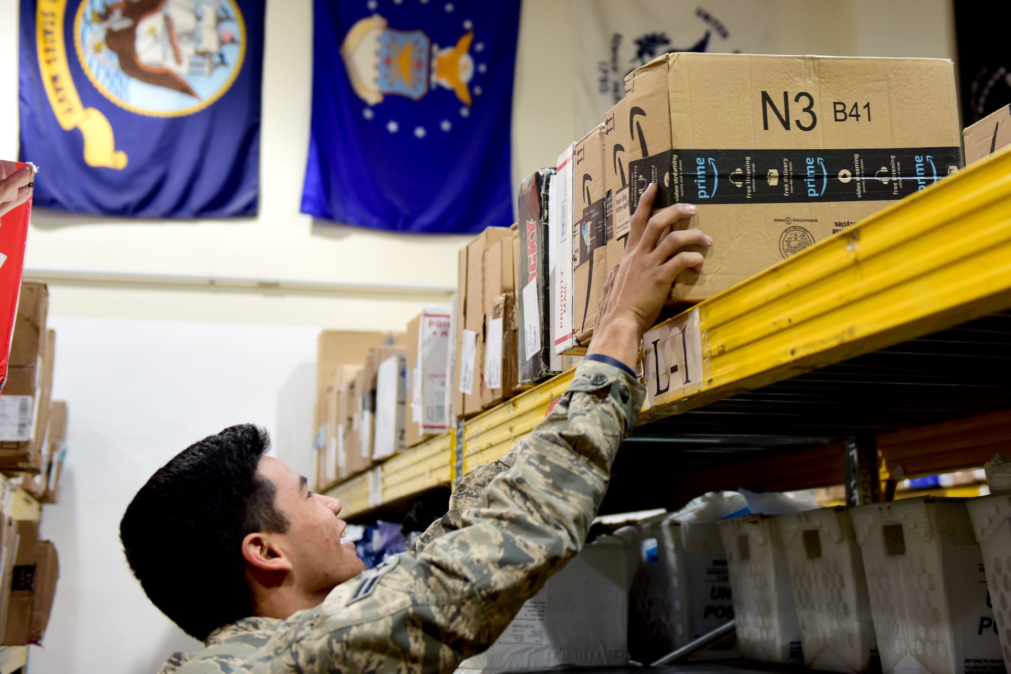 U.S. Air Force Airman 1st Class Daniel Young, 31st Force Support Squadron postal clerk, places packages onto a shelf at the Aviano Post Office, Aviano Air Base, Italy, March 25, 2020. The post office receives packages for service members, dependents, and civilians assigned to the base. (U.S. Air Force photo by Staff Sgt. Kelsey Tucker)