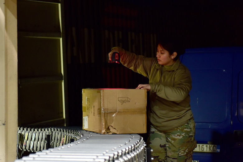 U.S. Air Force Staff Sgt. Eddith Guaman, 31st Force Support Squadron postal supervisor, scans an incoming package at the Aviano Post Office, Aviano Air Base, Italy, March 25, 2020. After unloading packages from the trucks, post office Airmen scan them into their system, sort them, and then either deliver them to members’ mailboxes or inform them via email that they have a package ready for pickup. (U.S. Air Force photo by Staff Sgt. Kelsey Tucker)