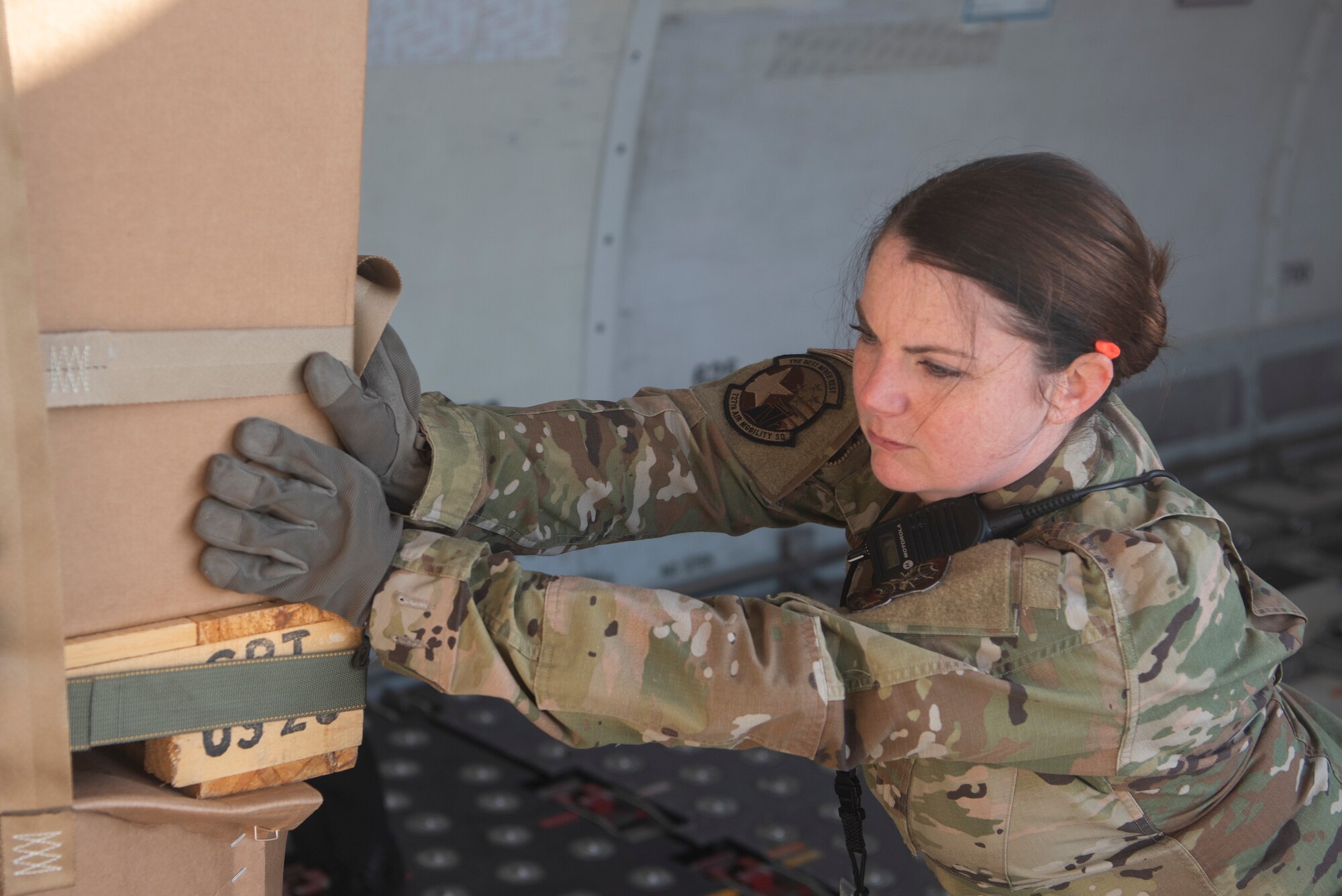 Tech. Sgt. Melissa Durkin-Willman, 727th Air Mobility Squadron noncommissioned officer in charge of passenger travels, pushes a cargo crate inside of a commercial aircraft March 24, 2020, at RAF Mildenhall, England. Air transportation Airmen must often rearrange cargo, as not all assets on board an aircraft are destined for the same location. (U.S. Air Force photo by Airman 1st Class Joseph Barron)