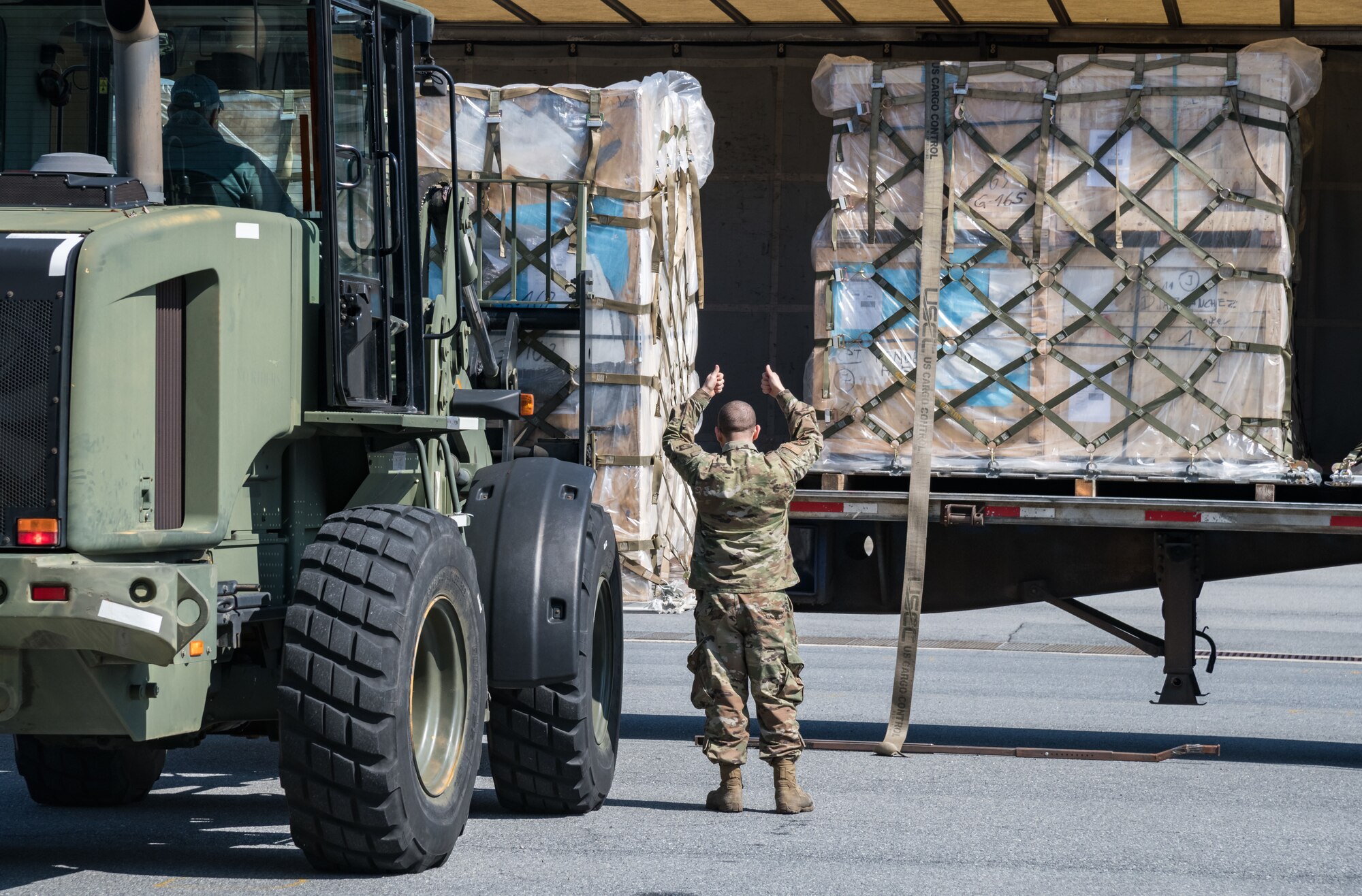 Airman 1st Class Emmanuel Arroyo, 436th Aerial Port Squadron traffic management office, marshals a 10K all-terrain forklift driven by Eric Banks, 436th APS, as they load a pallet onto a trailer March 26, 2020, at Dover Air Force Base, Delaware. Arroyo and Banks loaded numerous pallets onto the trailer as required airlift operations continued during the evolving COVID-19 pandemic. (U.S. Air Force photo by Roland Balik)
