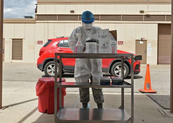 A photo of a medical technician Airman wearing protective gear from head-to-toe preparing COVID-19 sample kits