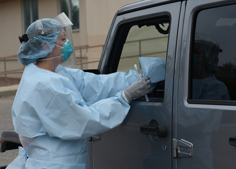 A photo of an Air Force nurse in protective gear in the process of collecting a sample from a patient