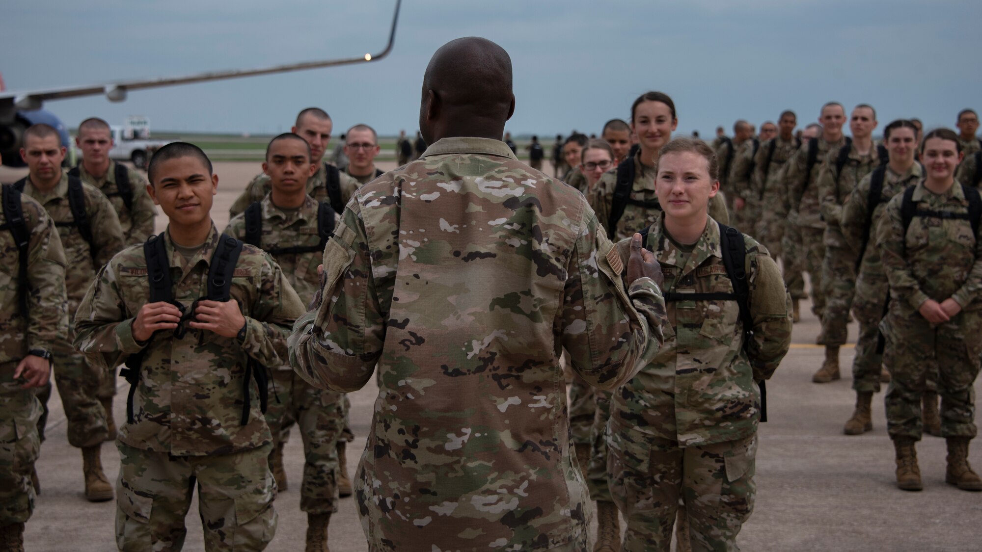Col. Kenyon Bell, 82nd Training Wing commander, briefs the newest basic military training graduates once they off load from a plane at Sheppard Air Force Base, Texas, March 27, 2020. Bell greeted the newest Airmen by explaining why technical training continues as they are deemed mission essential and thanked the newest Airmen for their commitment to the Air Force. (U.S. Air Force photo by Senior Airman Pedro Tenorio)