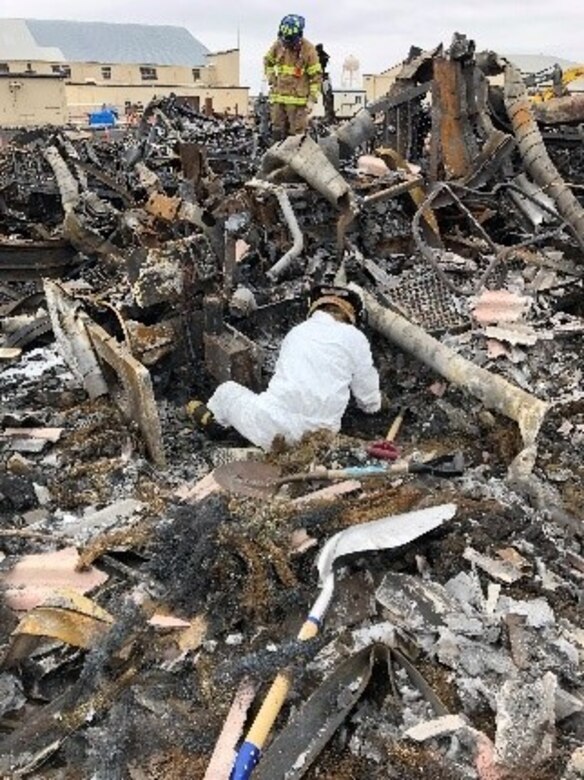 On Dec. 28, 2019, a fire gutted a Strategic Air Command-era hangar on Miniot Air Force Base, N.D. Office of Special Investigations Detachment 813 and 2nd Field Investigations Squadron teamed with the Bureau of Alcohol, Tobacco, Firearms and Explosives to conduct the subsequent investigation. Here, Investigator Jesse Gomez, foreground, and Special Agent Andrew Weinzierl sift through the rubble to determine the origin and cause of the blaze resulting in a $7M loss to the Air Force. (Photo by SA Leonard Meadows, OSI Det 813)