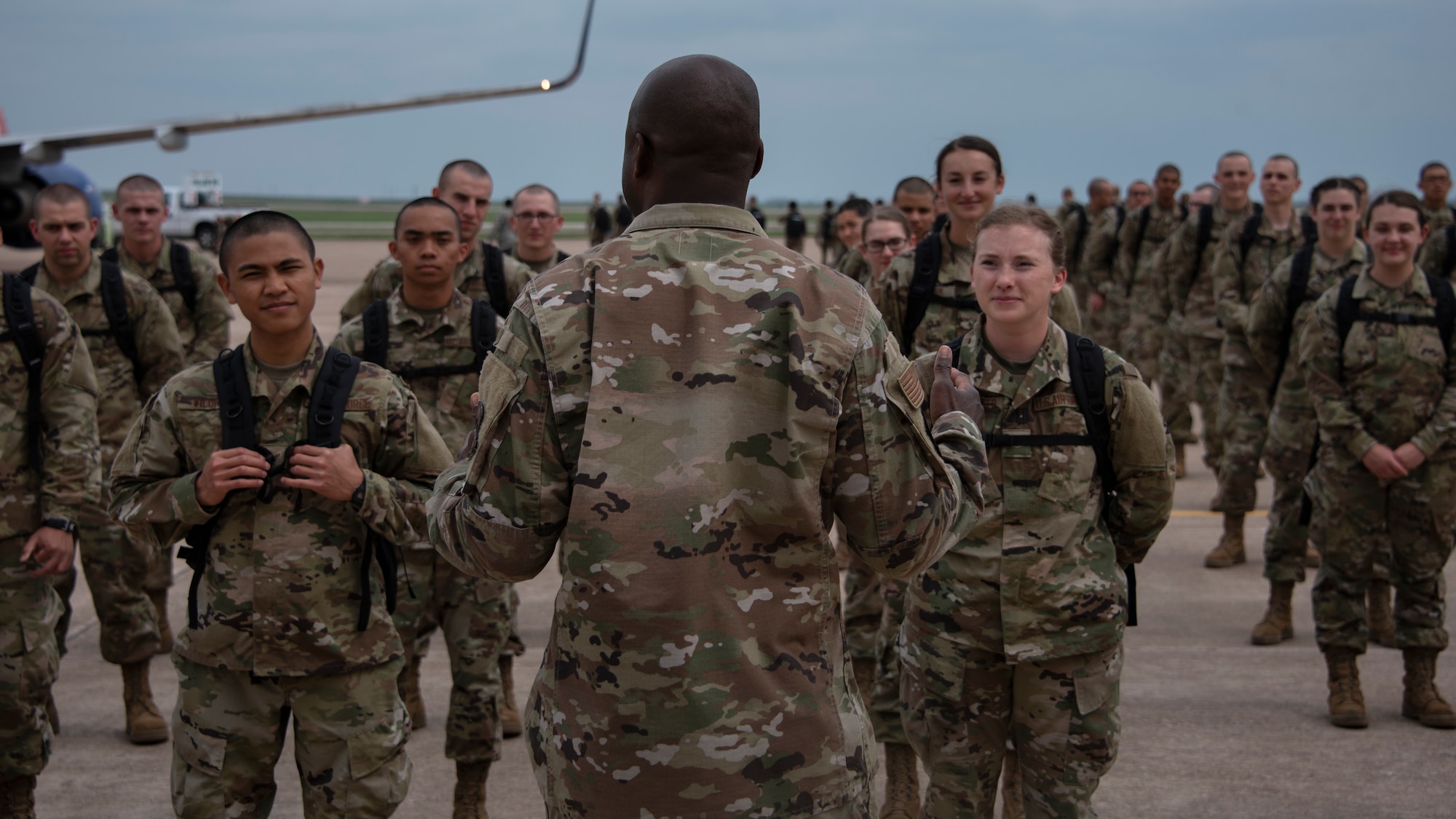 Col. Kenyon Bell, 82nd Training Wing commander, briefs the newest basic military training graduates once they off load from a plane at Sheppard Air Force Base, Texas, March 27, 2020. Bell greeted the newest Airmen by explaining why technical training continues as they are deemed mission essential and thanked the newest Airmen for their commitment to the Air Force. (U.S. Air Force photo by Senior Airman Pedro Tenorio)