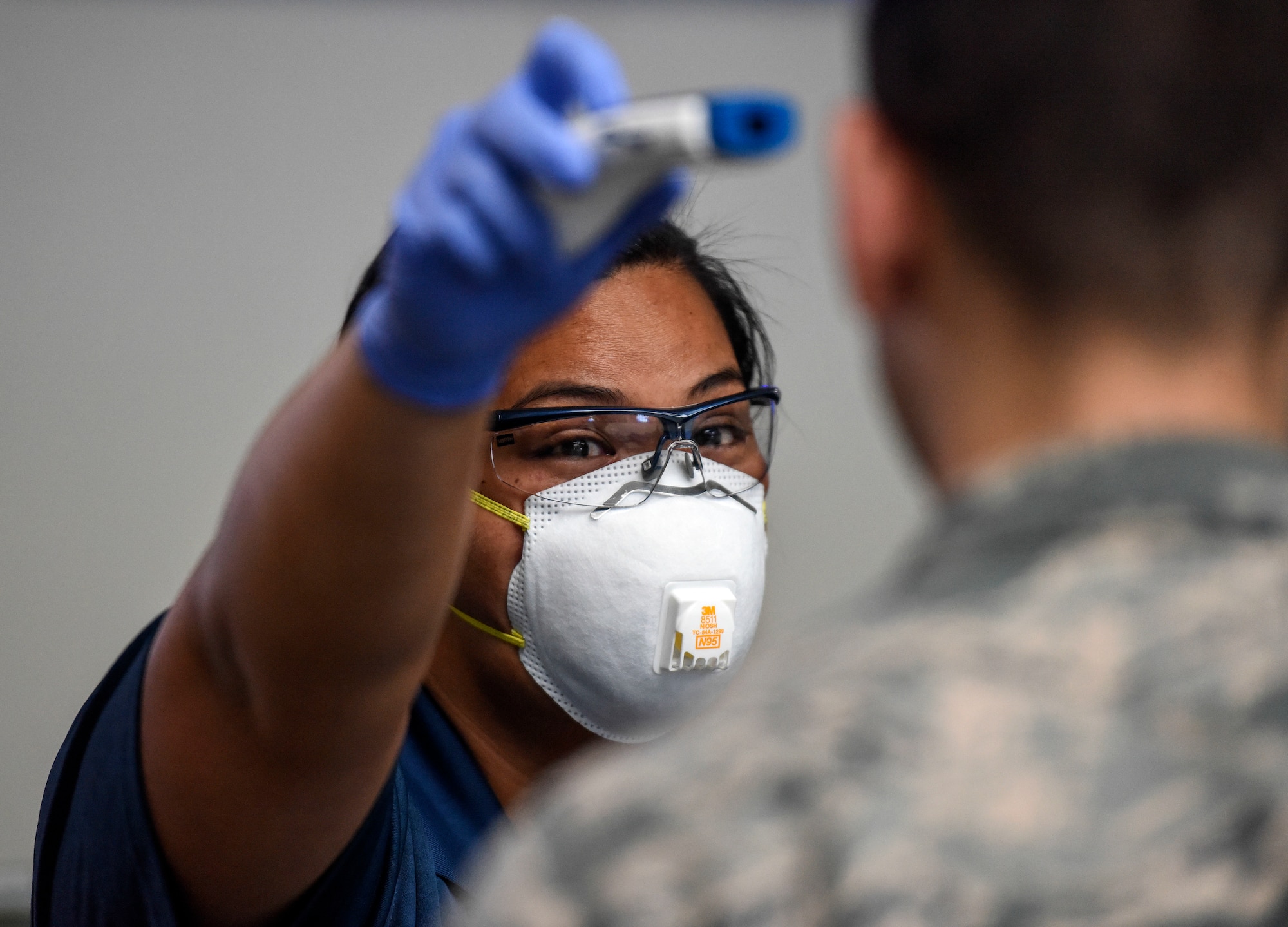 Kuhina Talimalie, 735th Air Mobility Squadron passenger service and baggage agent, tests a no-touch thermometer on an Airman at the Air Mobility Command Passenger Terminal at Joint Base Pearl Harbor-Hickam, Hawaii, March 25, 2020. Passenger terminal Airmen are screening passengers for fevers to help mitigate the spread of COVID-19. (U.S. Air Force photo by Tech. Sgt. Anthony Nelson Jr.)