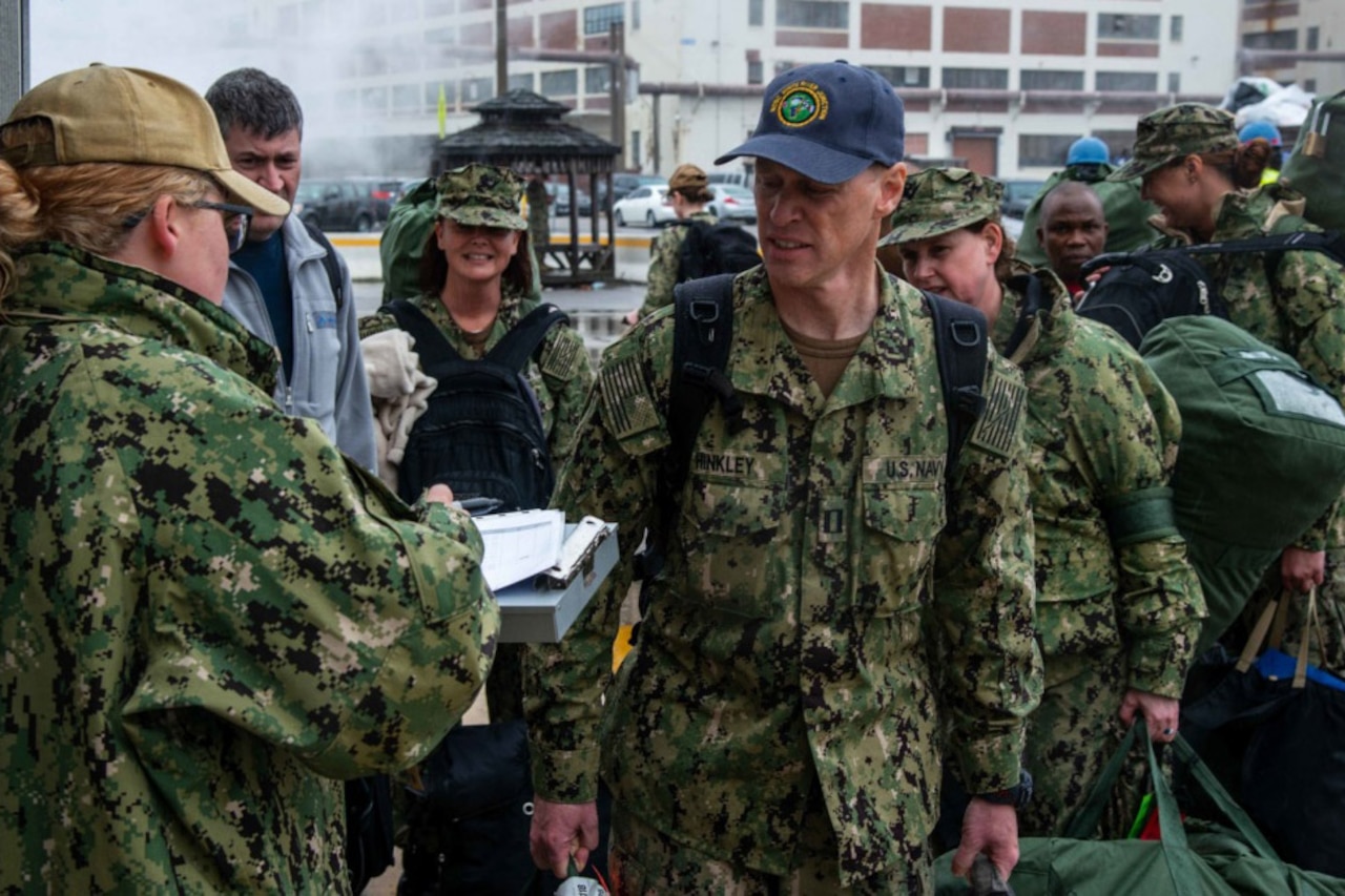 Reservists in camouflage uniforms stand in line to check in.