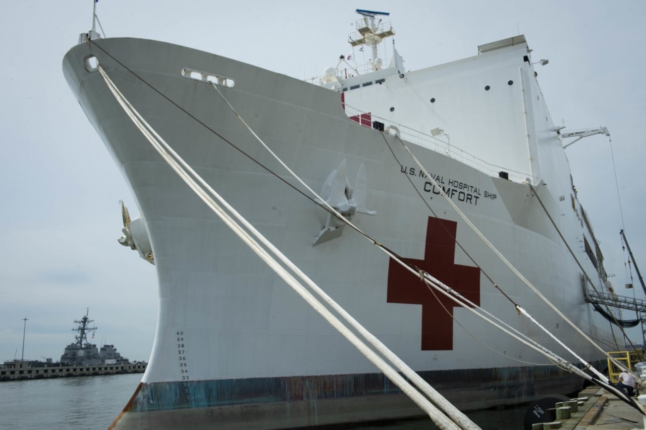 The bow of a large white ship with a red cross and lettering that says, “U.S. Naval Hospital Ship Comfort.”