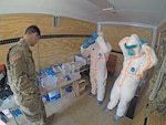 The California Army National Guard’s Pfc. Michael Daggi of the California National Guard Medical Detachment instructs California Emergency Medical Service Authority (EMSA) staff members on properly applying personal protective equipment March 27 at a San Mateo County, California, COVID-19 treatment facility.