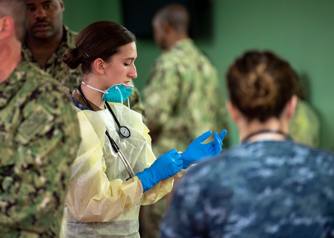 Sailor puts on a pair of blue surgical gloves.