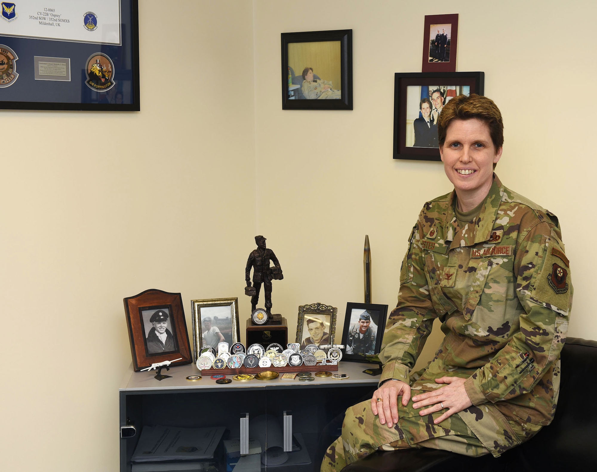 Colonel Michelle Estes, 352nd Special Operations Maintenance Group commander, poses for a photo with pictures of her family, several members of which have also served in the military, at RAF Mildenhall, England, March 18, 2020. As part of Women's History Month, Estes shared her experiences and life lessons from her 23-year career in the Air Force. (U.S. Air Force photo by Karen Abeyasekere)