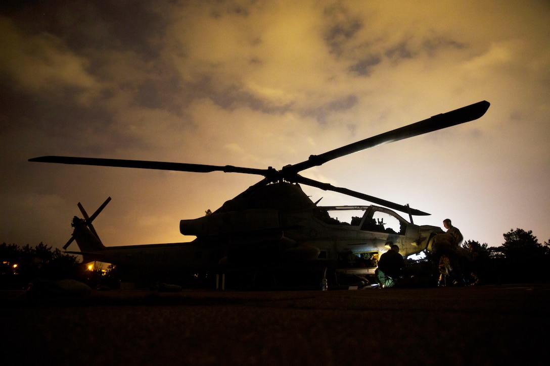 Marines work around a helicopter at twilight.