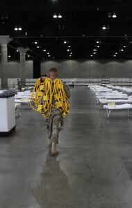 U.S. Air Force Tech. Sgt. Jarrett Boyd, a structures supervisor with the California Air National Guard's 146th Airlift Wing, sets up power cords in support of a federal medical station for COVID-19 response at the Los Angeles Convention Center, March 29, 2020. The wing set up additional medical stations in the California cities of Indio and Santa Clara.