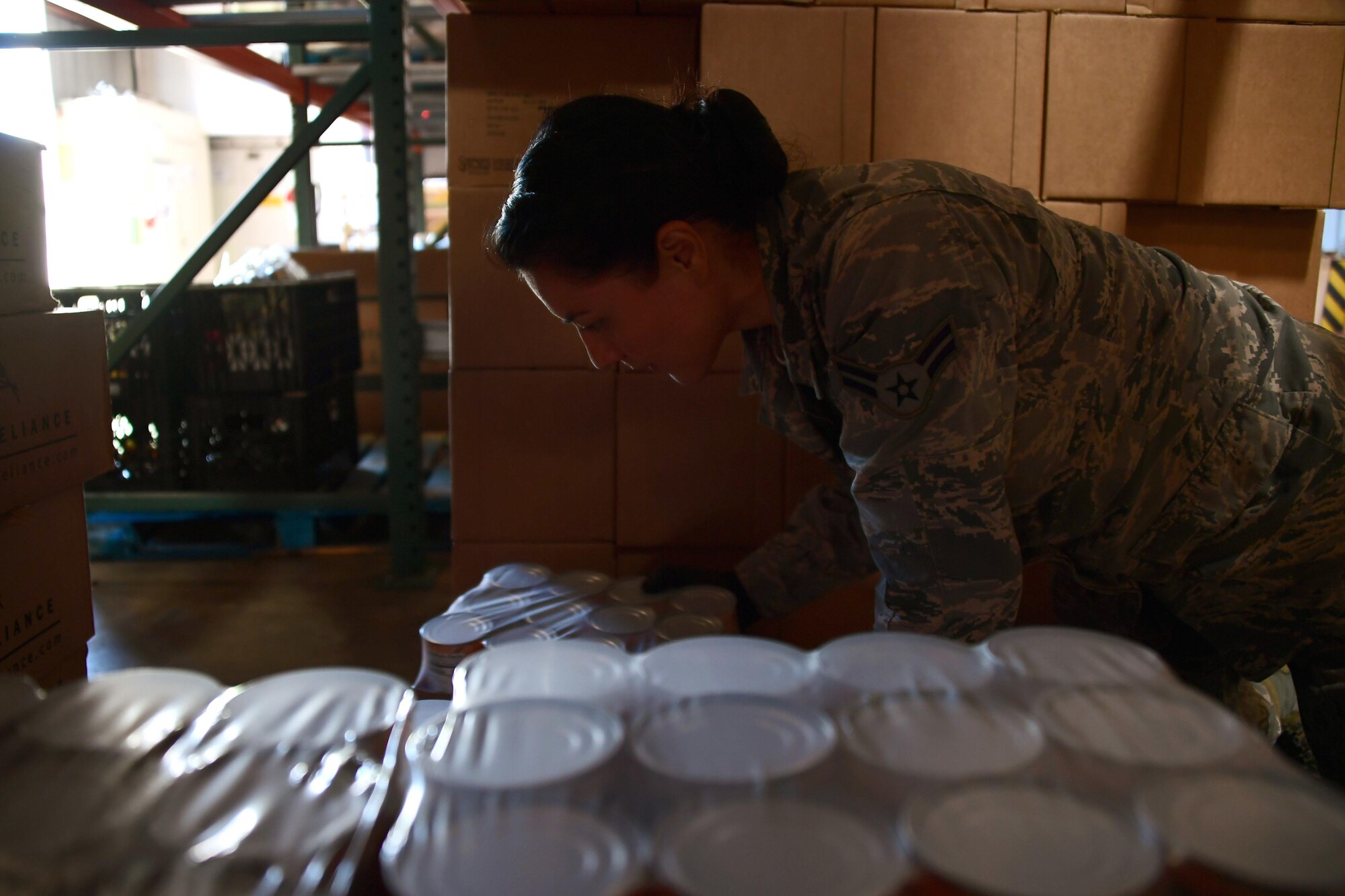 A picture of U.S. Air National Guard Airman 1st Class Blanca Alvarez preparing a case of canned food to be delivered to a food distribution facility.