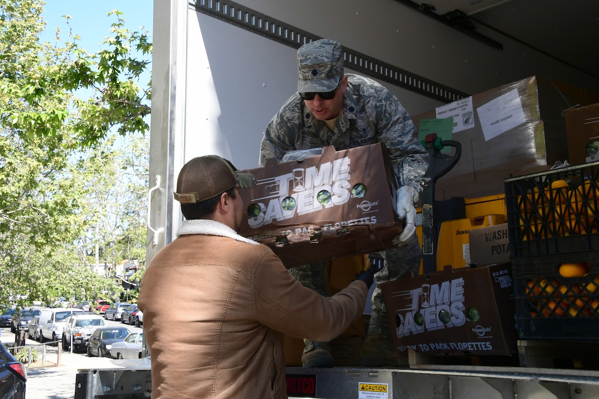 U.S. Air National Guard Lt. Col. Adam Goldstone from the 146th Airlift Wing’s Medical Group unloads donated food from the back of a Foodbank Santa Barbara County delivery truck at the West Boys and Girls Club in Santa Barbara, California. March 27, 2020. California Air National Guard members helped deliver food to distribution centers.