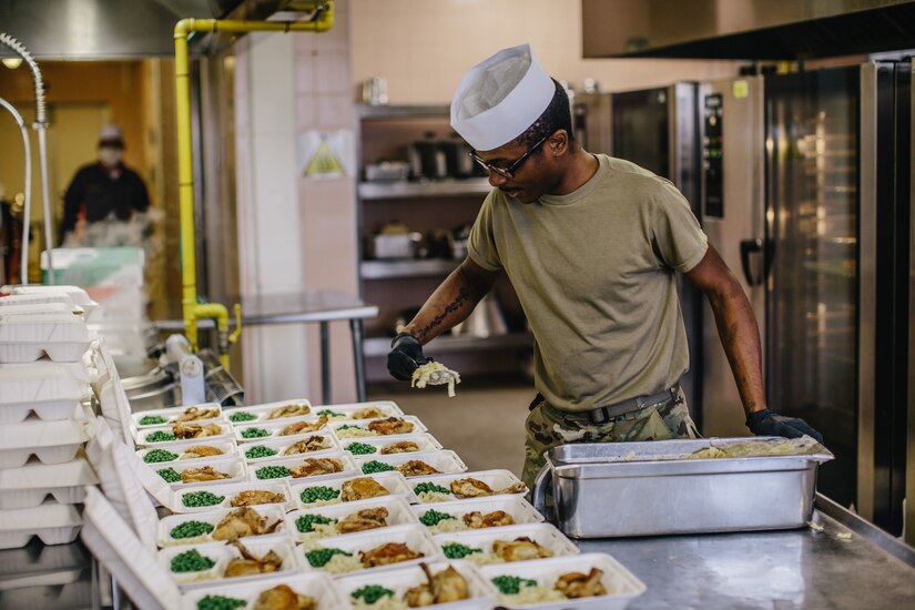 A soldier prepares food in a kitchen.