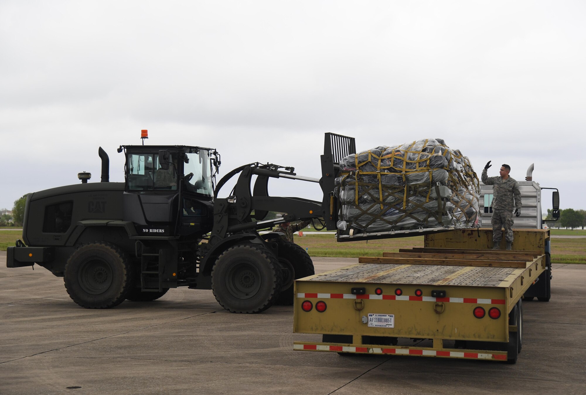 A pallet of duffel bags being loaded on a flat bed truck.