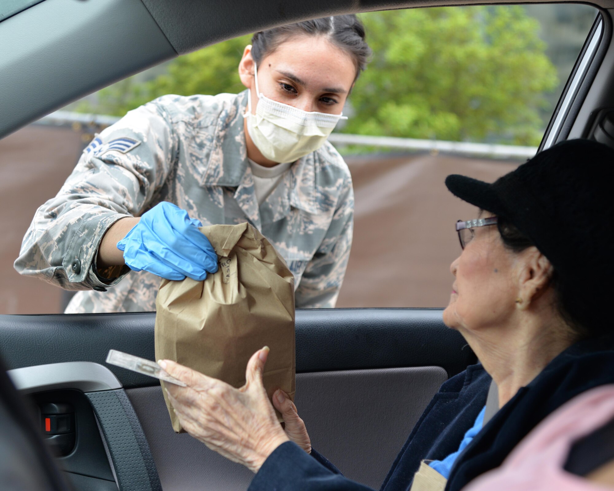 U.S. Air Force Senior Airman Reanne Kohlus, a dental technician assigned to the 59th Dental Group, hands a prescription over to a beneficiary at Joint Base San Antonio- Lackland, Texas, March 30, 2020. The 59th Medical Wing is providing curbside service until further notice in front of the Wilford Hall Ambulatory Surgical Center in support of social distancing recommendations and to increase efforts to mitigate further spread of the novel coronavirus. (U.S. Air Force photo by Kiley Dougherty)