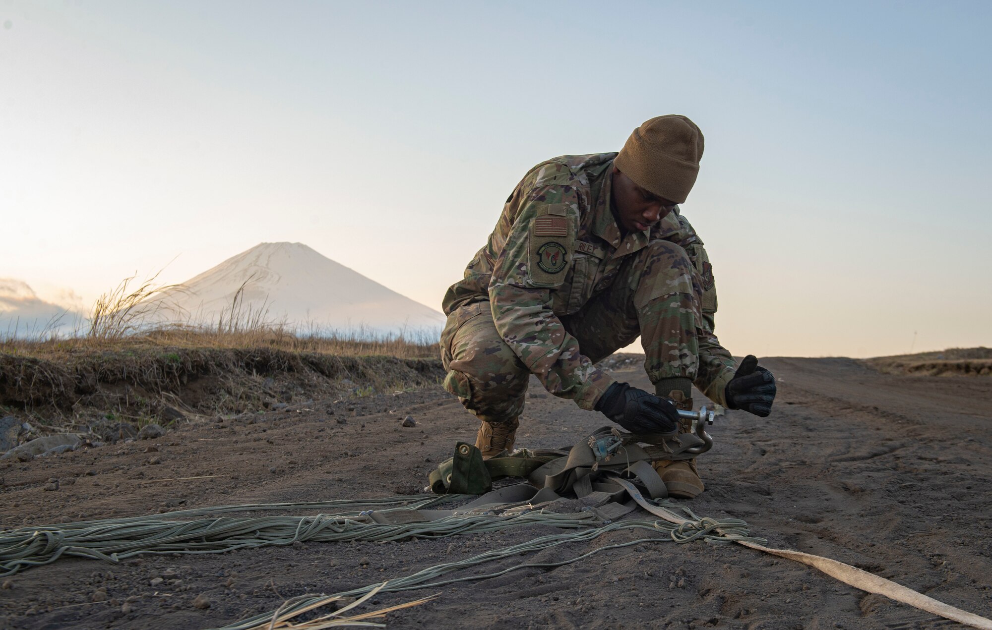 Airman 1st Class Jalen Riley, 374th Logistics Readiness Squadron combat mobility flight technician, removes debris from a canopy and suspension lines before stowing the parachute inside a recovery bag