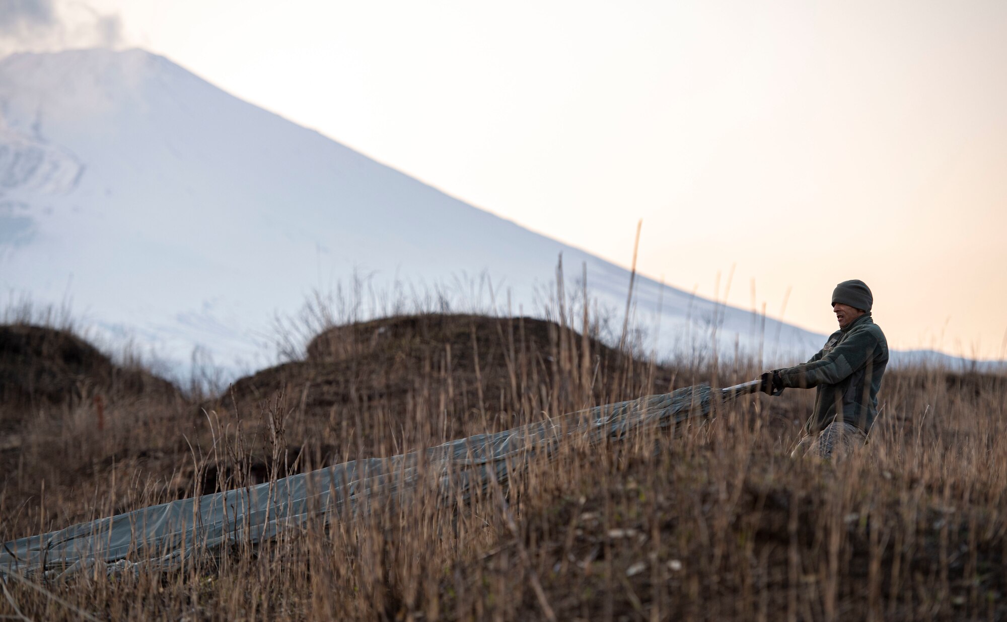 Senior Airman Devin Fox, 374th Logistics Readiness Squadron combat mobility flight technician, pulls a parachute canopy from the weeds before preparing it to be stowed inside a recovery bag