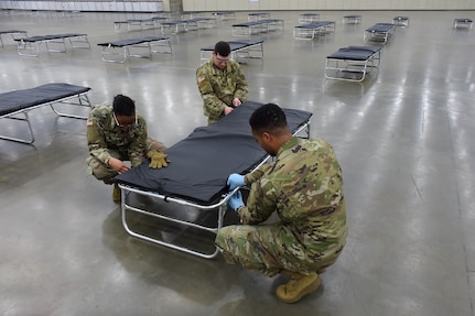 Soldiers with the Maryland Army National Guard assemble a cot while setting up a federal medical station in the Baltimore Convention Center March 28, 2020, to alleviate possible overcrowding at area hospitals as a result of the COVID-19 outbreak. About 15,000 National Guard members are on duty nationwide delivering supplies, running mobile testing centers and working with state and local authorities.