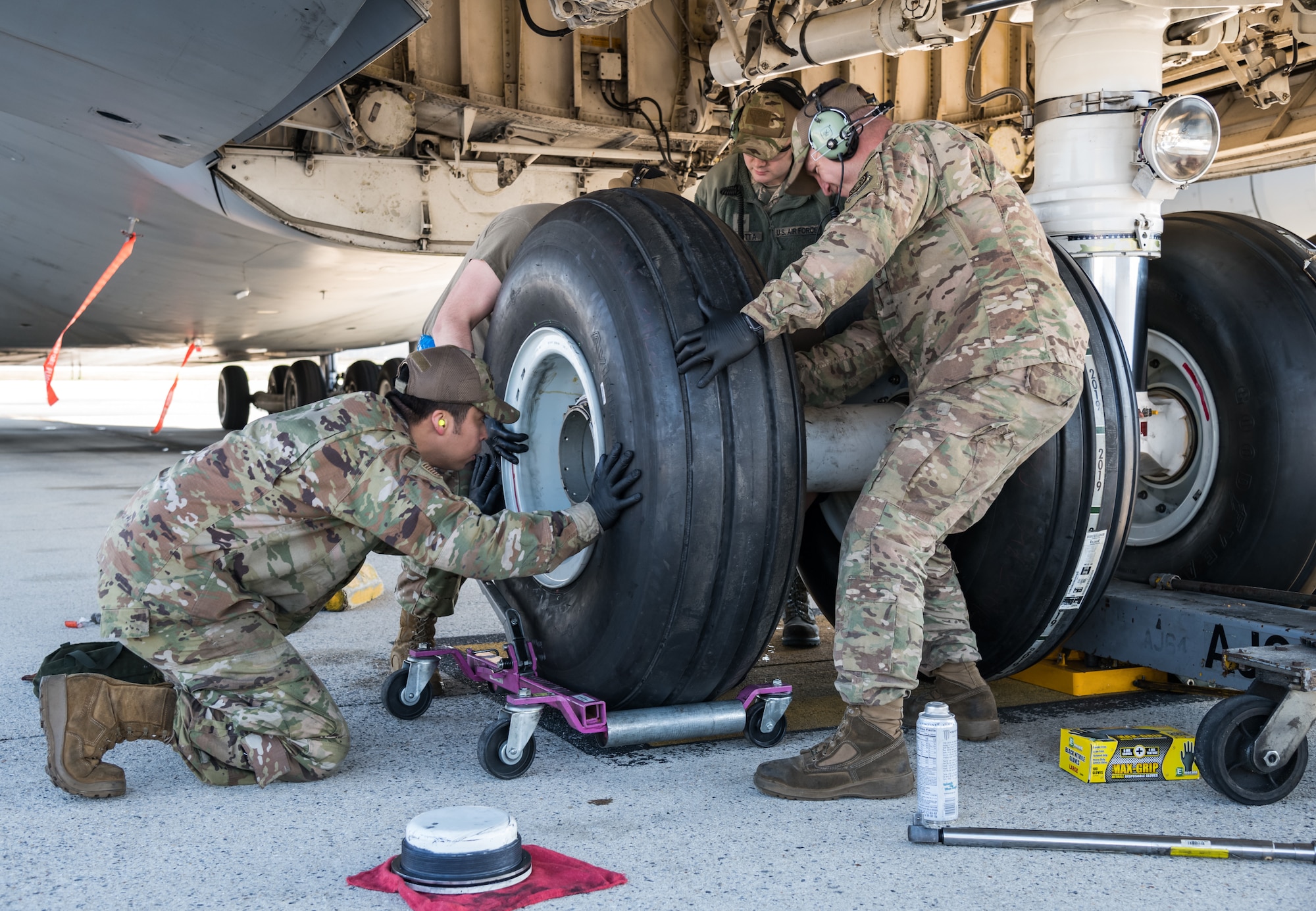 Tech. Sgt. Rendy Diaz Vargas, left, 436th Aircraft Maintenance Squadron crew chief, lines up a nose tire onto the axle of a C-5M Super Galaxy March 26, 2020, on Dover Air Force Base, Delaware. During the changing of the tire, Diaz Vargas and other maintainers from the 436th and 512th AMXS wore approved Operational Camouflage Pattern (OCP) bump caps and observed social distancing practices, while performing maintenance on the Super Galaxy. (U.S. Air Force photo by Roland Balik)