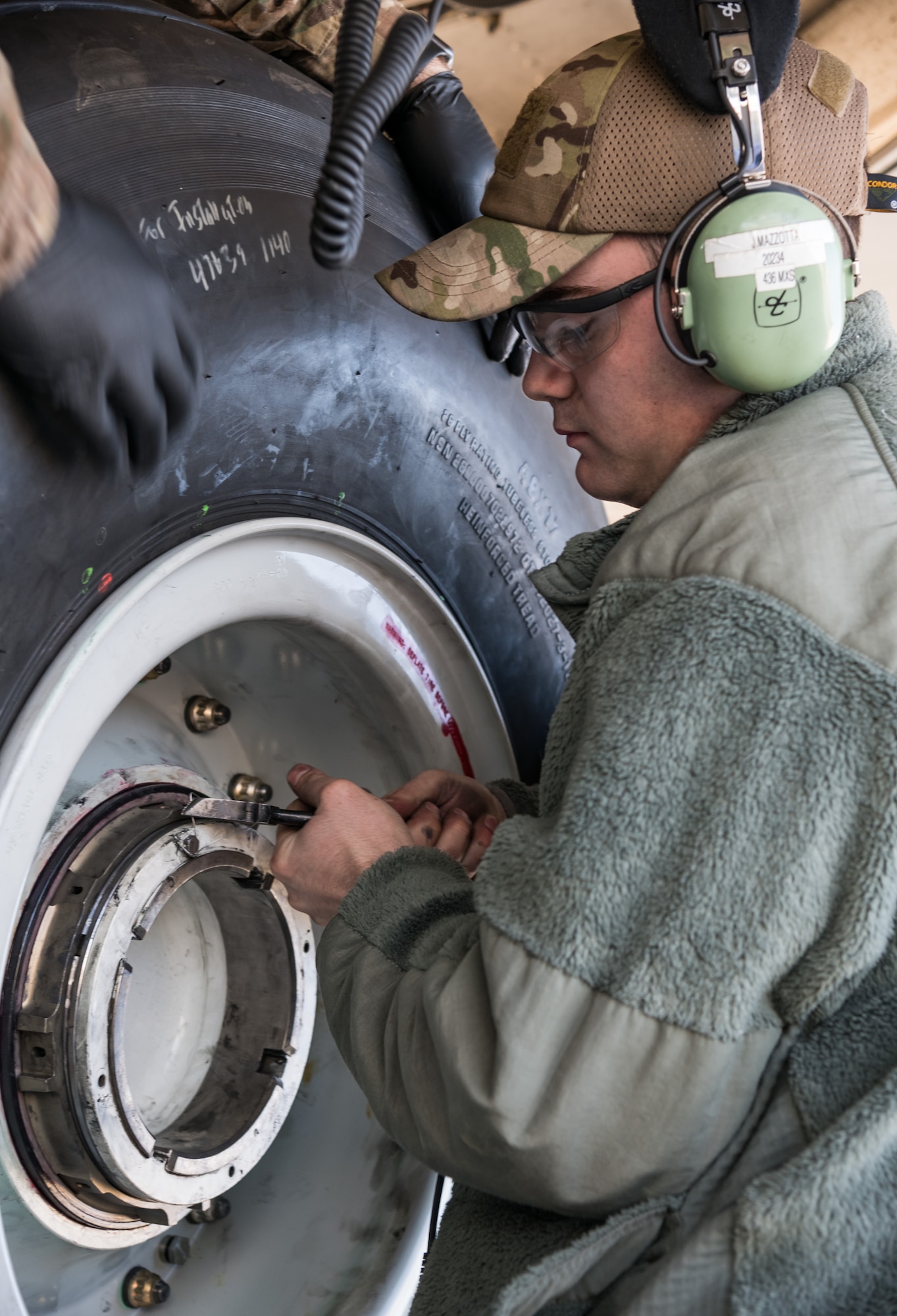 Senior Airman Jeffrey Mazzotta, 436th Aircraft Maintenance Squadron hydraulics journeyman, safety-wires a bolt on a C-5M Super Galaxy nose landing gear axle March 26, 2020, on Dover Air Force Base, Delaware. Mazzotta and other members of his crew wore approved Operational Camouflage Pattern (OCP) bump caps and observed social distancing practices during a tire change on the Super Galaxy. (U.S. Air Force photo by Roland Balik)