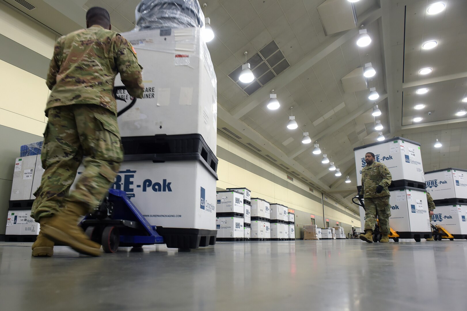 Soldiers with the Maryland Army National Guard move boxes containing bedding and medical supplies into position as they and other Soldiers set up a federal medical station in the Baltimore Convention Center March 28, 2020. They are part of a force of about 15,000 National Guard members on duty nationwide delivering supplies, running mobile testing centers and working with state and local authorities in COVID-19 response efforts.