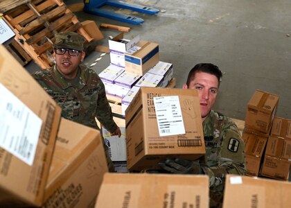 Spc. Alexander Cruz-Martinez and Staff Sgt. Carey Morris, New Hampshire Army National Guard, load boxes of personal protective equipment onto a military cargo truck in Concord.