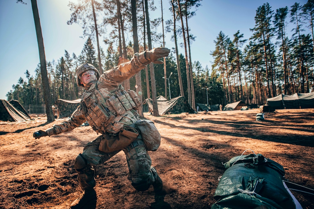 A soldier winds up to throw a grenade.