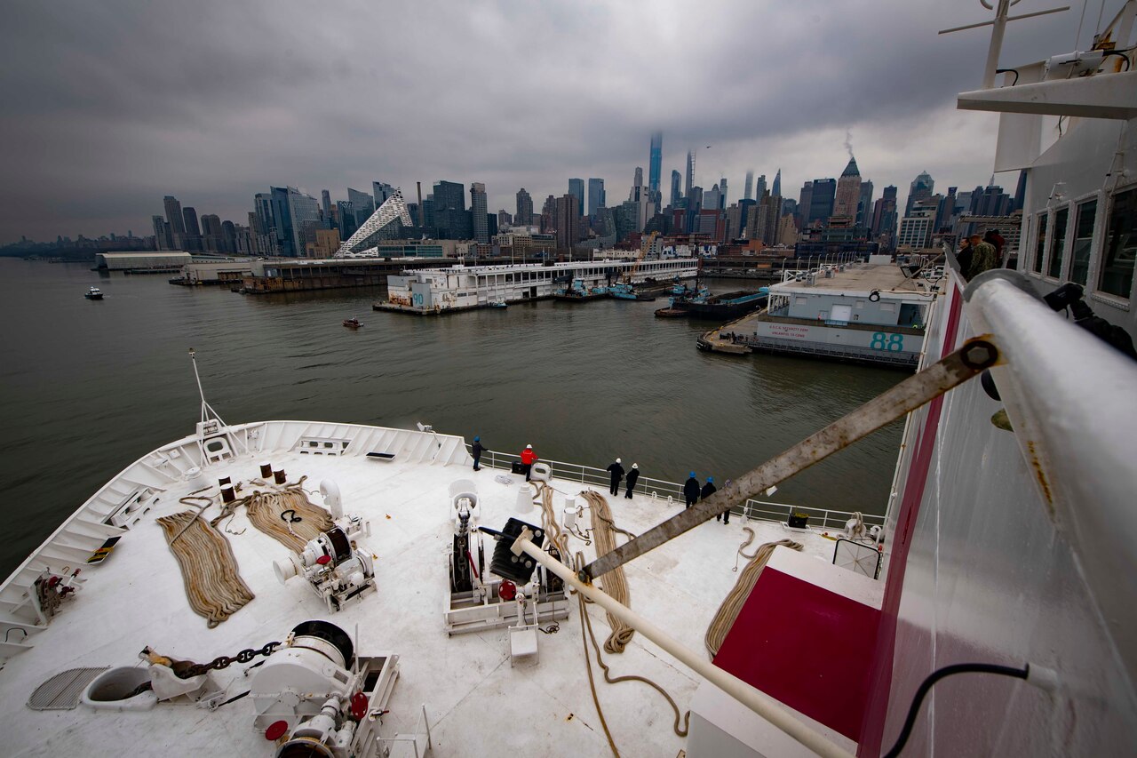 Sailors look at the New York City skyline as their ship arrives.