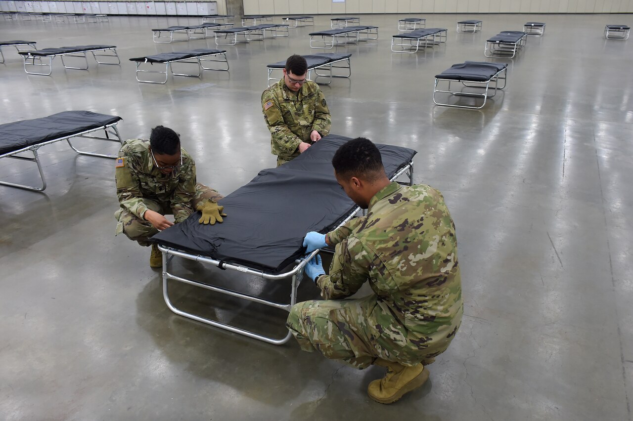 Soldiers assemble cots.