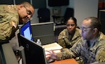 Members of the New York Army National Guard discuss procedures at the Coronavirus Hotline call center in Hawthorne, N.Y., March 16, 2020. The New York State Department of Health established a toll-free Coronavirus Hotline (1-888-364-3065).