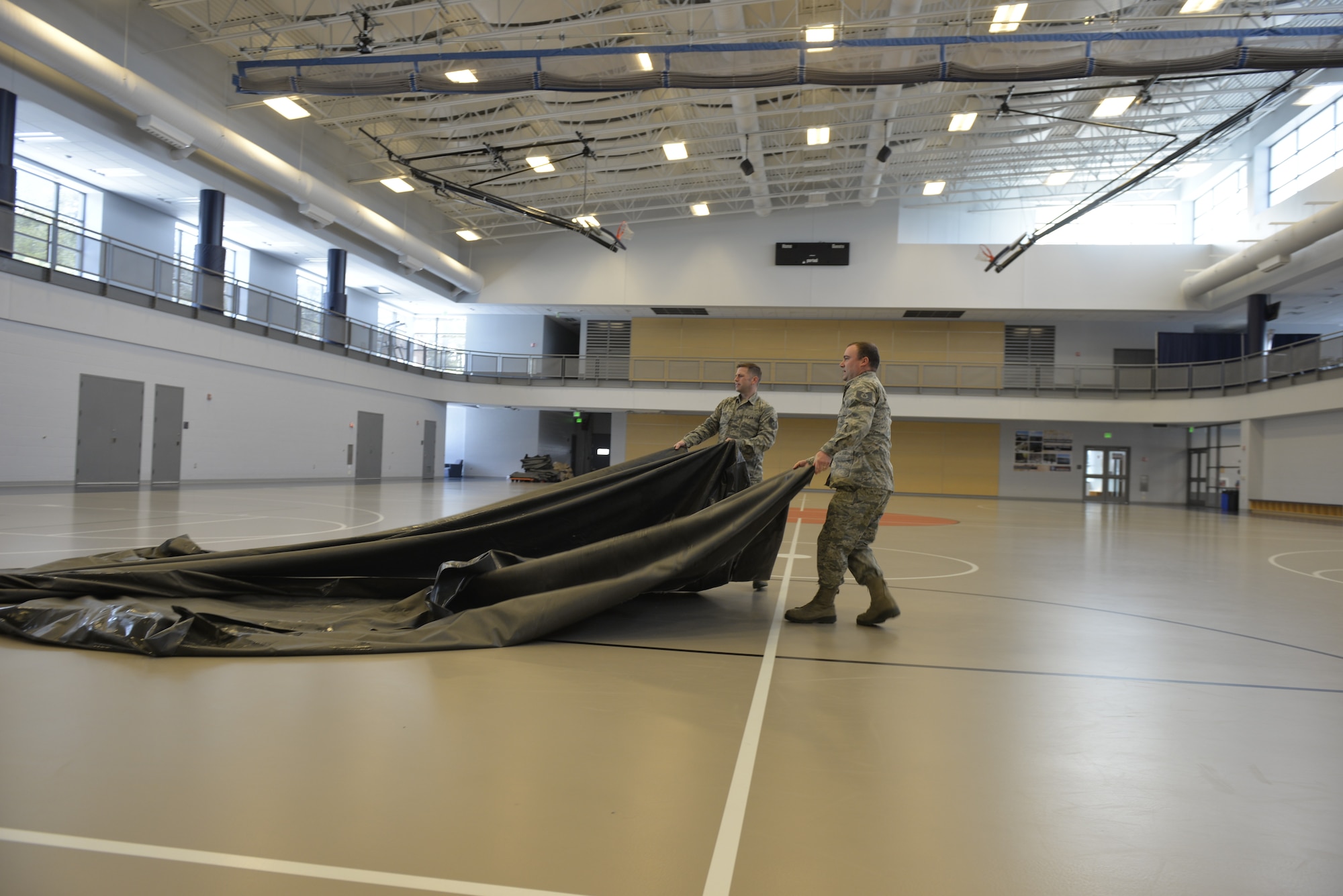Tech. Sgt. Mark Quinn and Tech. Sgt. Lance Whitehill, assigned to the 157th Civil Engineer Squadron, New Hampshire Air National Guard, prepare the Hamel Recreational Center floor for medical equipment at the University of New Hampshire, March 25. The facility in Durham will augment area hospitals treating COVID-19 cases, if necessary. It is one of nine "surge" locations the NH Guard, in coordination with local and state healthcare agencies, plans to set up and manage across the state. (U.S. Air National Guard photo by Tech. Sgt. Aaron Vezeau)