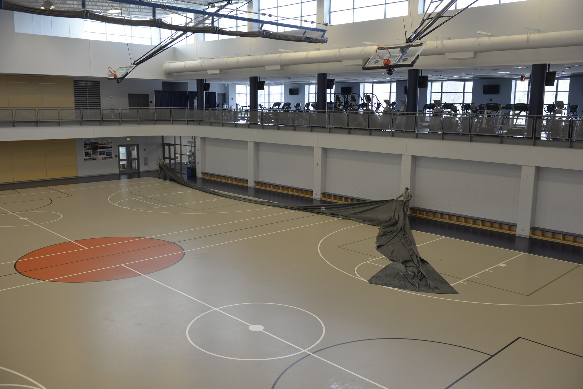 U.S. Air Force Tech. Sgt. Lance Whitehill and Tech. Sgt. Mark Quinn, 157th Civil Engineer Squadron, lay down matting at Hamel Recreation Center gym floor, March 25, 2020, at the University of New Hampshire. The facility will augment area hospitals treating COVID-19 cases, if necessary. It is one of nine the NHNG plans to set up and manage across the state. (U.S. Air National Guard photo by Tech. Sgt. Aaron Vezeau)