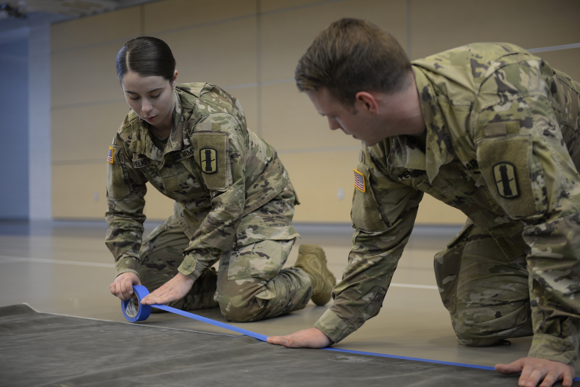 Pvt. Mackenzie Pelkey, a fire control specialist, 197th Fires Artillery Brigade, and Sgt. Robert Peterson, a motor transportation operator, 744th Forward Support Company, New Hampshire Army National Guard, help prepare the floor of the Hamel Recreation Center at the University of New Hampshire, March 25, 2020. The facility will augment area hospitals treating COVID-19 cases, if necessary. It is one of nine the New Hampshire National Guard plans to set up and manage across the state. (U.S. Air National Guard photo by Tech. Sgt. Aaron Vezeau)