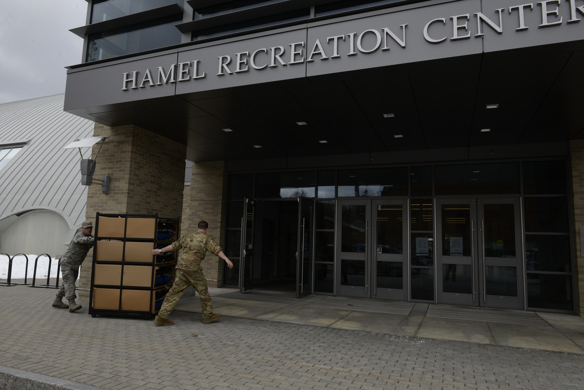 Tech. Sgt. Lance Whitehill, 157th Civil Engineers Squadron, and Capt. Jacob Ricciotti, 157th Operations Group, New Hampshire Air National Guard, bring medical supplies into the Hamel Recreation Center at the University of New Hampshire, March 25, 2020. The facility will augment area hospitals treating COVID-19 cases, if necessary. It is one of nine the NHNG plans to set up and manage across the state. (U.S. Air National Guard photo by Tech. Sgt. Aaron Vezeau)