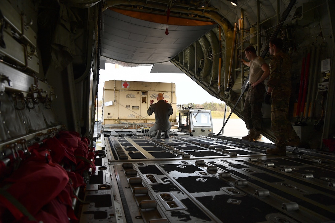 Airman guides pallet full of supplies on aircraft.