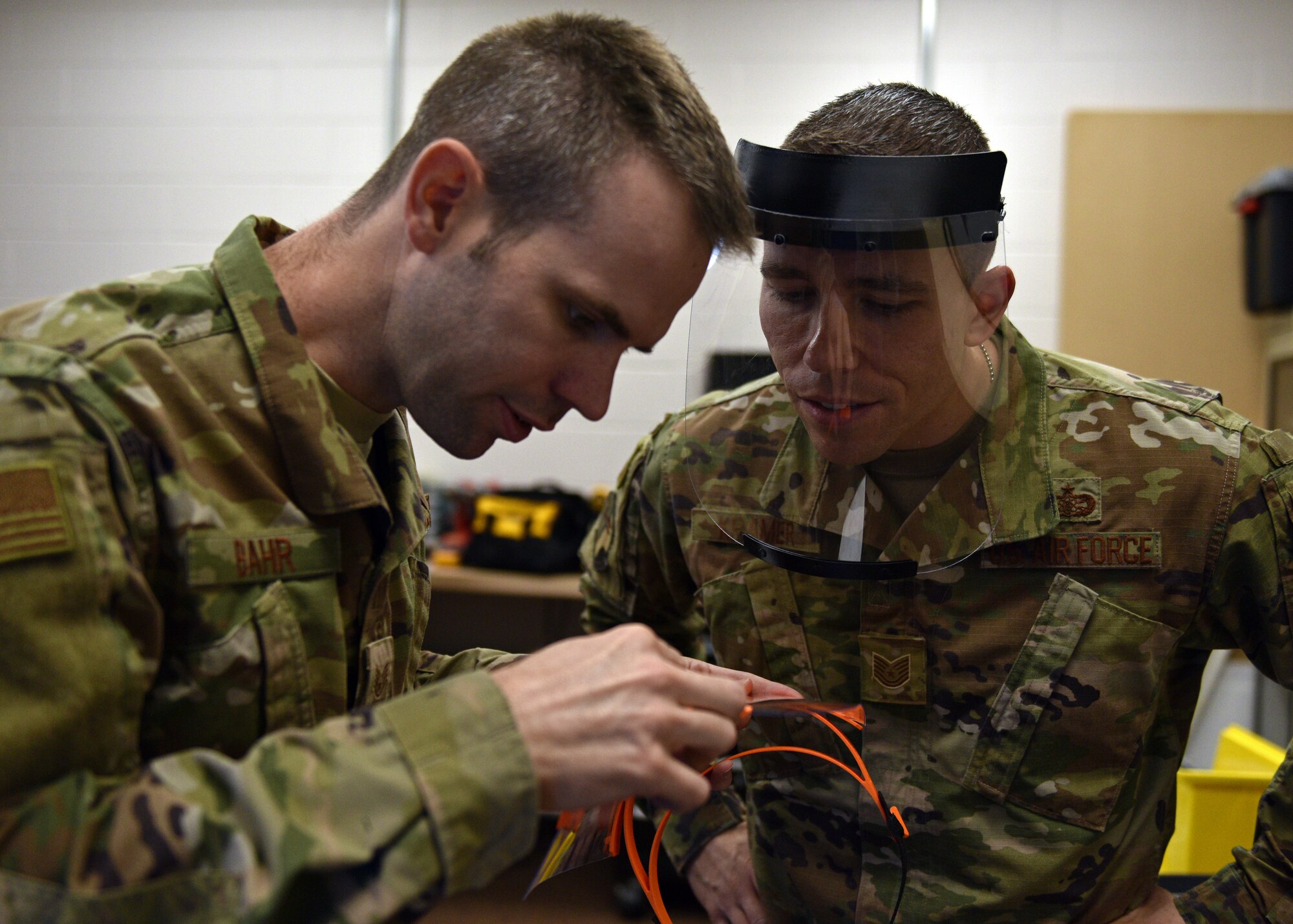 U.S. Air Force Staff Sgt. Jonathan Bahr, 312th Training Squadron Special Instruments Training course instructor, and Tech. Sgt. Donald Kramer, 312th TRS SPINSTRA instructor supervisor, prepare and don  3D printed face shields at the Louis F Garland Department of Defense Fire Academy on Goodfellow Air Force Base, Texas, March 31, 2020. The instructors got the idea after seeing other organizations modeling and printing these supplies to provide for medical facilities. (U.S. Air Force photo by Airman 1st Class Robyn Hunsinger)