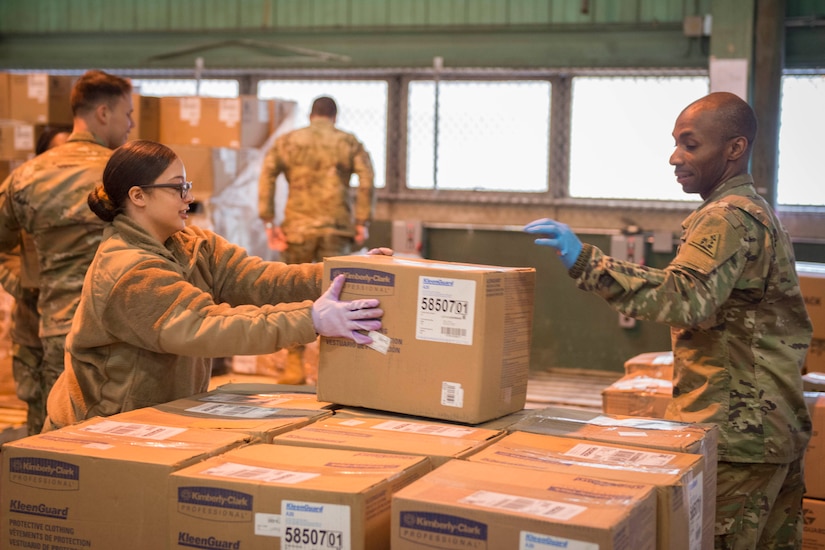 Guardsmen organize boxes in a warehouse.